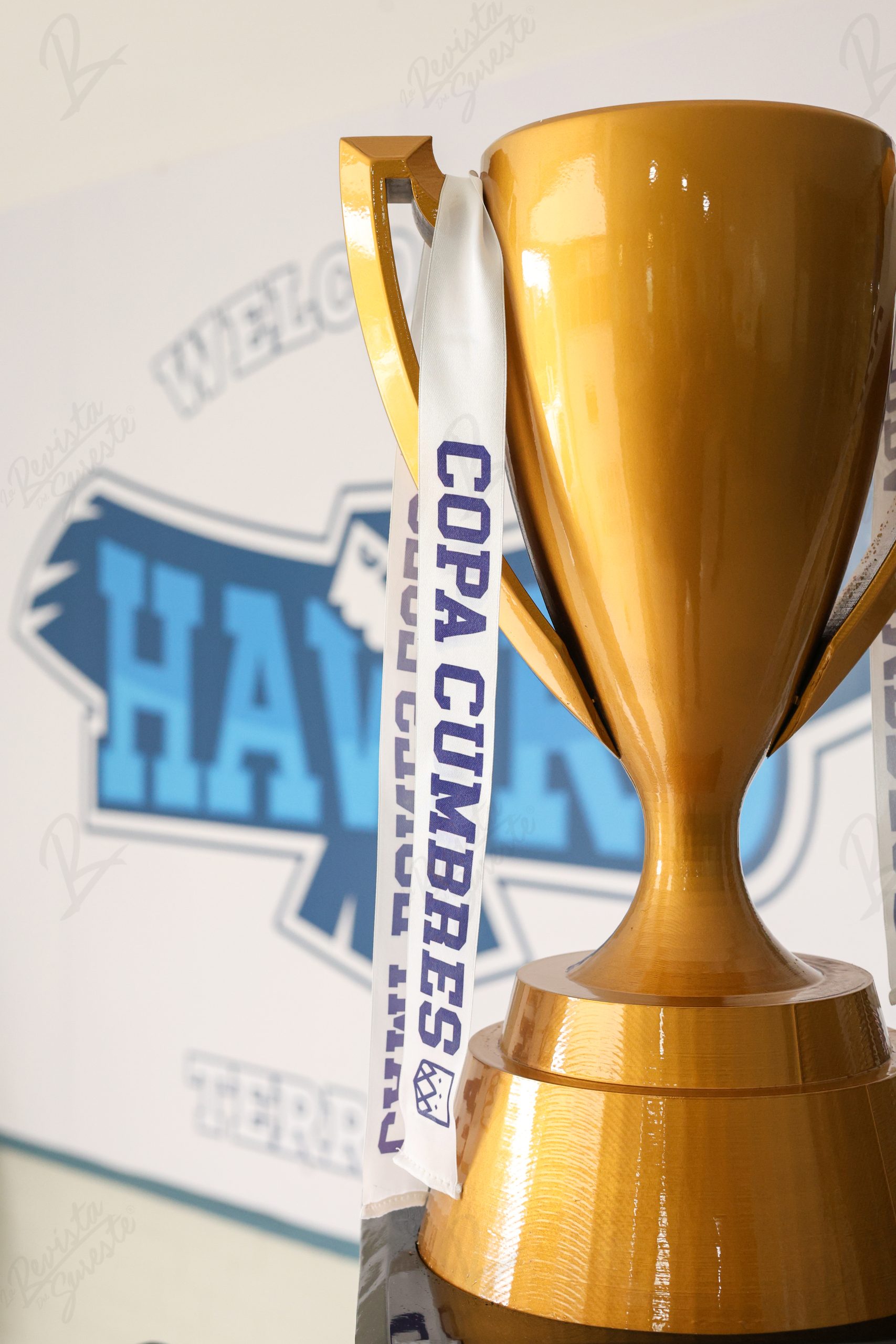 Un Trofeo Dorado Con Acabado Brillante. Del Asa Cuelga Una Cinta Blanca Con El Texto &Quot;Copa Cumbres Villahermosa&Quot; En Letras Azules.