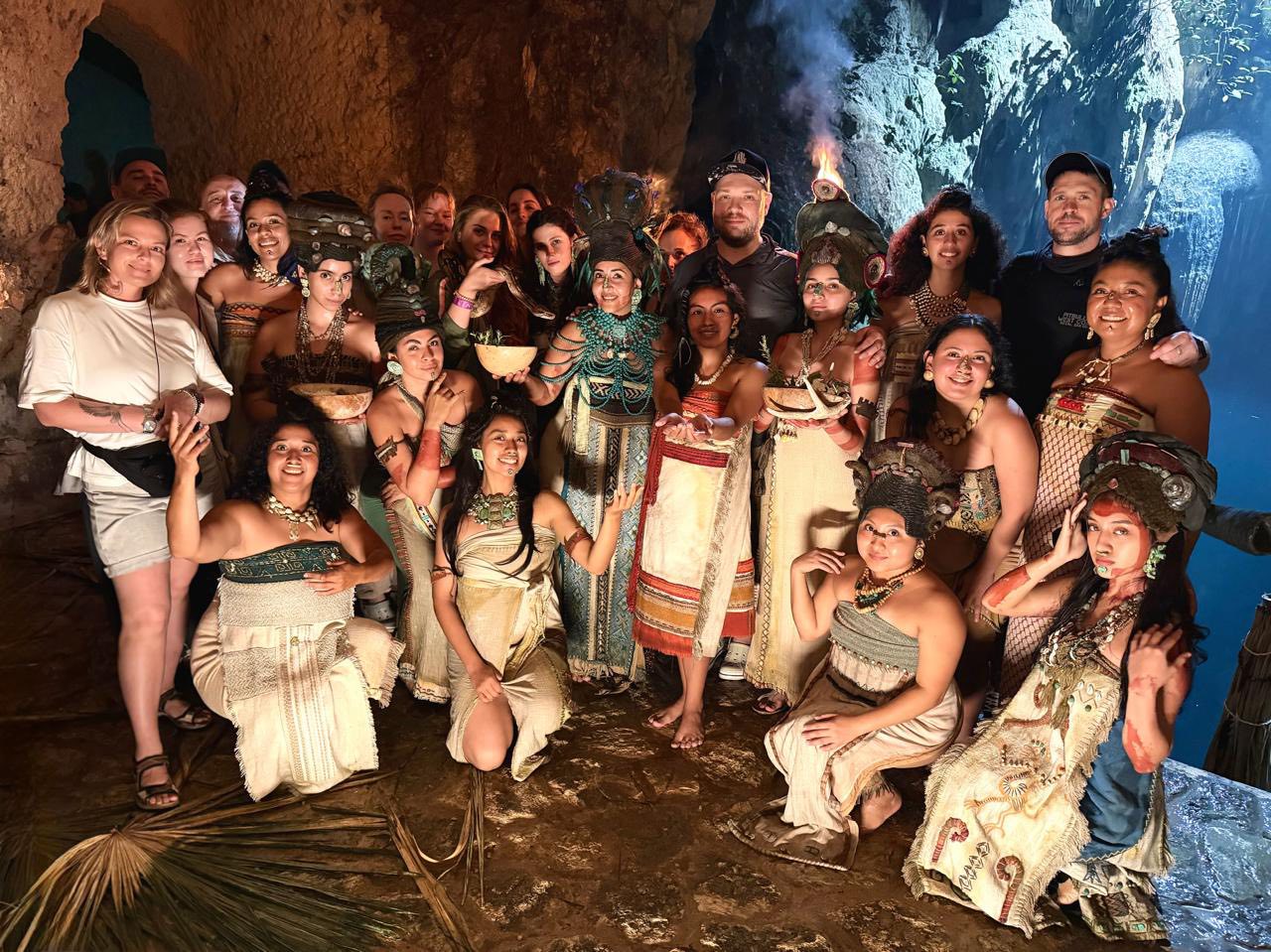 De san petersburgo a la selva maya: el embajador de rusia visita el rodaje de la biografía de yuri knórosov en yucatán la revista del sureste mx Fotografía Grupal Del Elenco Y Equipo De Producción De La Película Rusa “Los Dioses De Knórosov” Dentro De Una Cueva En Yucatán. Un Grupo Numeroso De Mujeres Mexicanas Viste Indumentaria Tradicional Maya Con Penachos, Collares De Cuentas Y Vestidos De Manta, Mientras Que El Equipo De Filmación Ruso Posa Junto A Ellas. La Escena Está Iluminada De Forma Cálida Dentro De Una Gruta Rocosa Con Un Cenote Al Fondo.