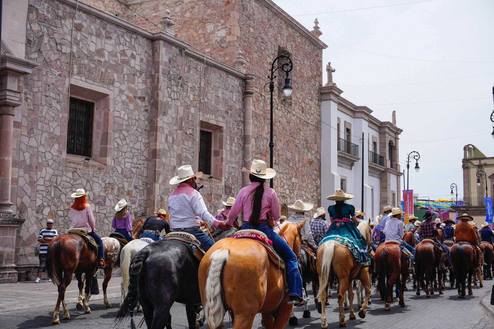 Magna cabalgata 2026: tradición y orgullo ecuestre en la feria de san marcos la revista del sureste mx Vista Desde Atrás De Un Contingente De Jinetes Y Escaramuzas Cabalgando Por Una Calle De Aguascalientes. Se Aprecian Sombreros Charros, Vaqueros Y Trajes Regionales.