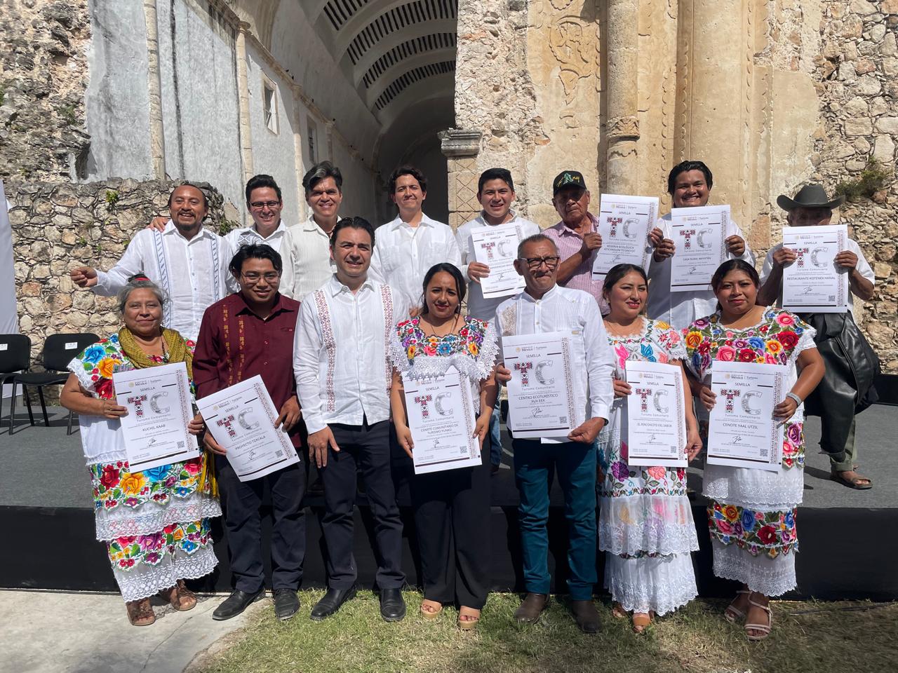 Yucatán se posiciona como líder nacional en turismo comunitario con 61 distintivos federales la revista del sureste mx Un Grupo De 13 Personas, Entre Hombres Y Mujeres De Origen Maya, Posan Sonrientes En Un Primer Plano Frente A La Estructura Histórica De Tihosuco. Visten Guayaberas Blancas Y Huipiles Tradicionales Con Bordados Florales Multicolores. Sostienen Con Orgullo Sus Certificados Oficiales Del &Quot;Distintivo De Turismo Comunitario&Quot; Nivel Semilla, Donde Se Leen Proyectos Locales Como &Quot;Cenote Yaal Utzil&Quot;, &Quot;Centro Ecoturístico X-Yaaj-Eek&Quot; Y &Quot;Kuchil Kaab&Quot;. En El Centro Del Grupo Se Encuentra Raúl Paz Noriega, Subsecretario De La Sefotur Yucatán, Brindando Respaldo Institucional Al Evento.
