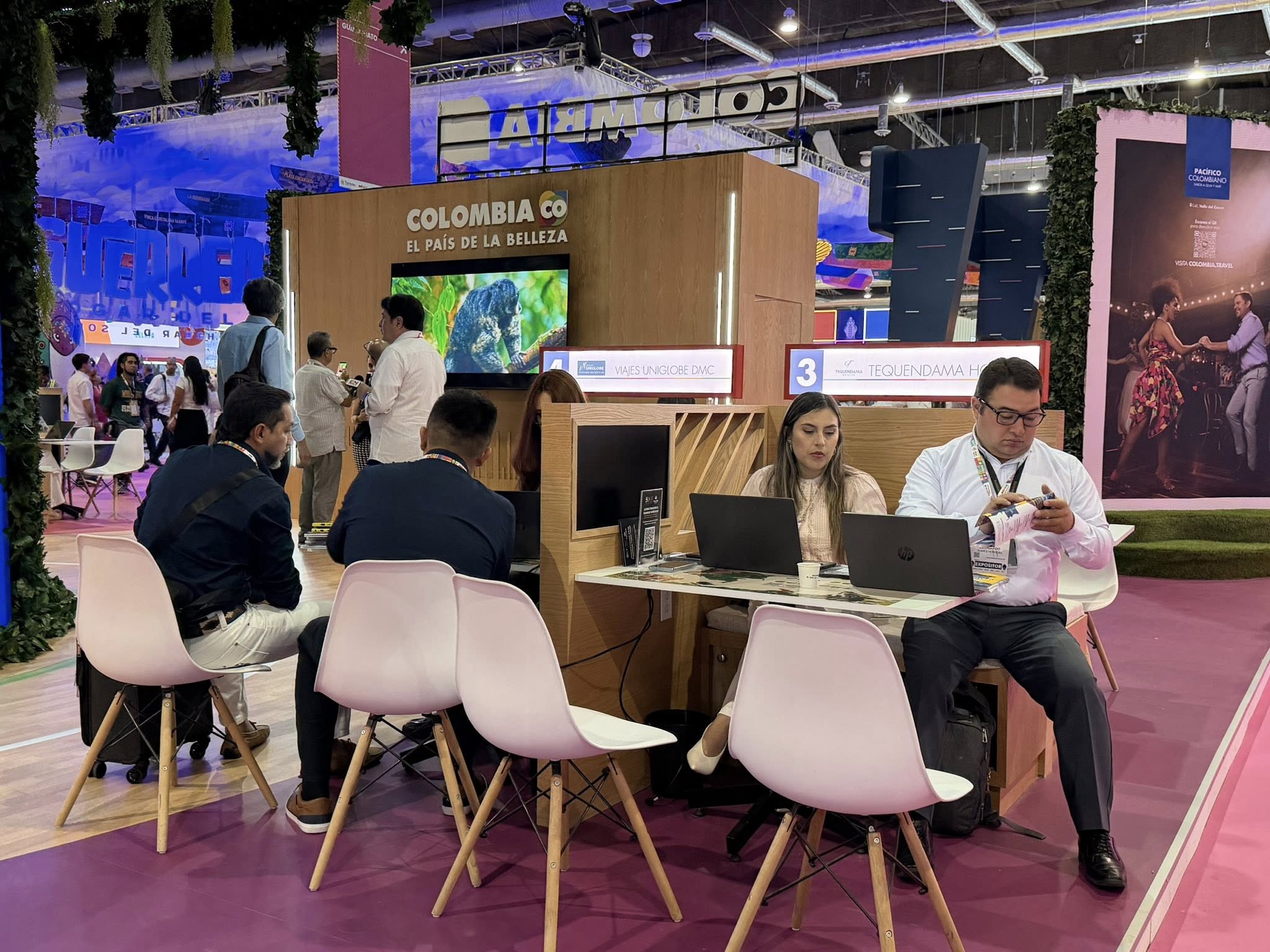Un Plano De Ángulo Medio Que Captura La Actividad En El Stand De Exhibición De &Quot;Colombia Co - El País De La Belleza&Quot; En Una Gran Feria Comercial Como El Tianguis Turístico.