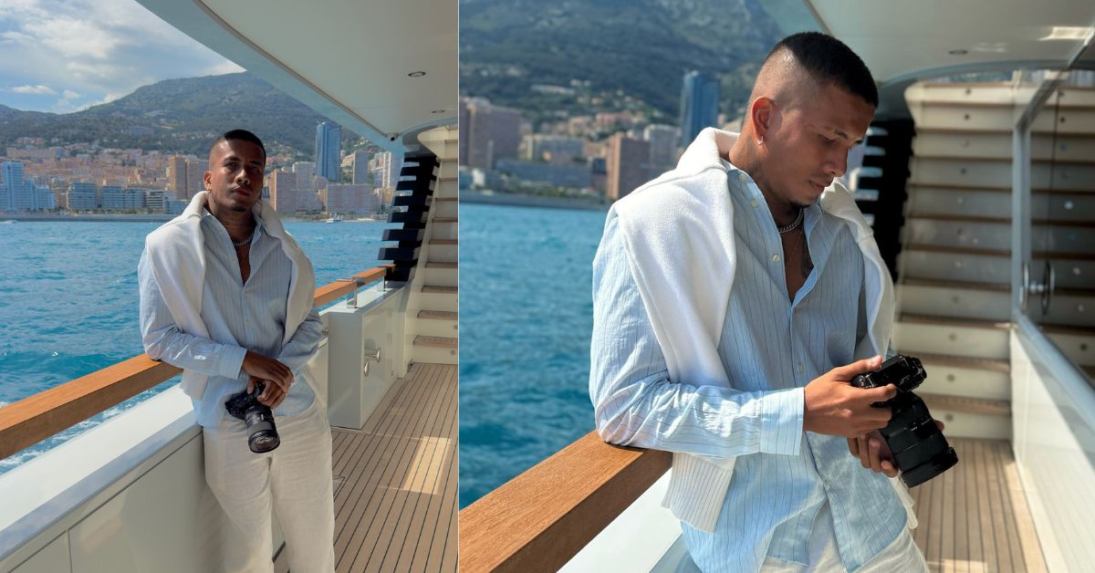 Un Díptico (Dos Fotos Juntas) Muestra Al Fotógrafo Juan Barcasnegras De Pie En La Cubierta De Un Lujoso Yate. Viste Una Camisa De Lino Azul Claro, Pantalones Blancos Y Lleva Un Suéter Blanco Sobre Los Hombros.