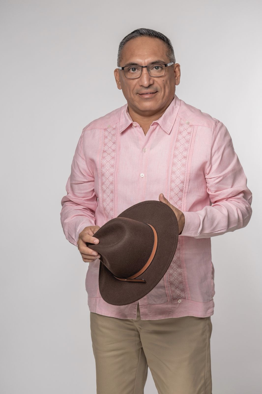 David asencio: el estratega del factor humano que transforma la seguridad y el liderazgo en el caribe mexicano la revista del sureste mx Retrato De Plano Medio De David Asencio Sobre Un Fondo Blanco Limpio. Viste Una Guayabera Tradicional De Color Rosa Claro Con Detalles De Bordado Vertical, Pantalones Color Caqui Y Anteojos De Armazón Oscuro.