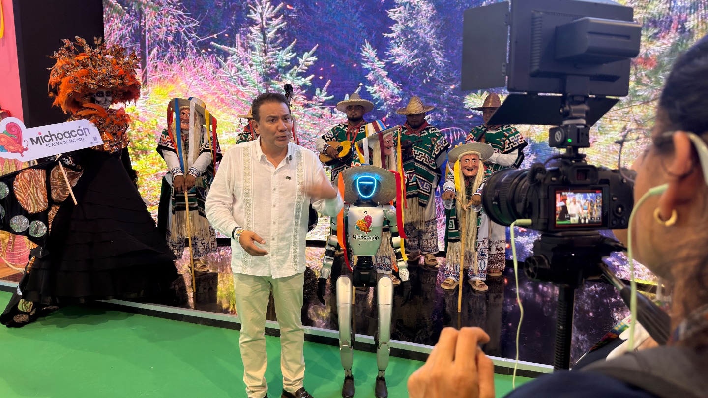 Un Robot Humanoide Con Sombrero Tradicional Y El Logo De Michoacán Posa Junto A Un Presentador Y Artistas Folclóricos En El Tianguis Turístico 2026.
