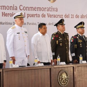 Autoridades Civiles Y Militares De Pie Frente A Un Presídium Durante La Ceremonia Conmemorativa De La Gesta Heroica Del Puerto De Veracruz. Al Centro Destaca El Gobernador De Tabasco, Javier May, Flanqueado Por Altos Mandos De La Secretaría De Marina Y La Secretaría De La Defensa Nacional En Uniformes De Gala. Al Fondo Se Observa Una Lona Con El Título Oficial Del Evento En Letras Guindas.