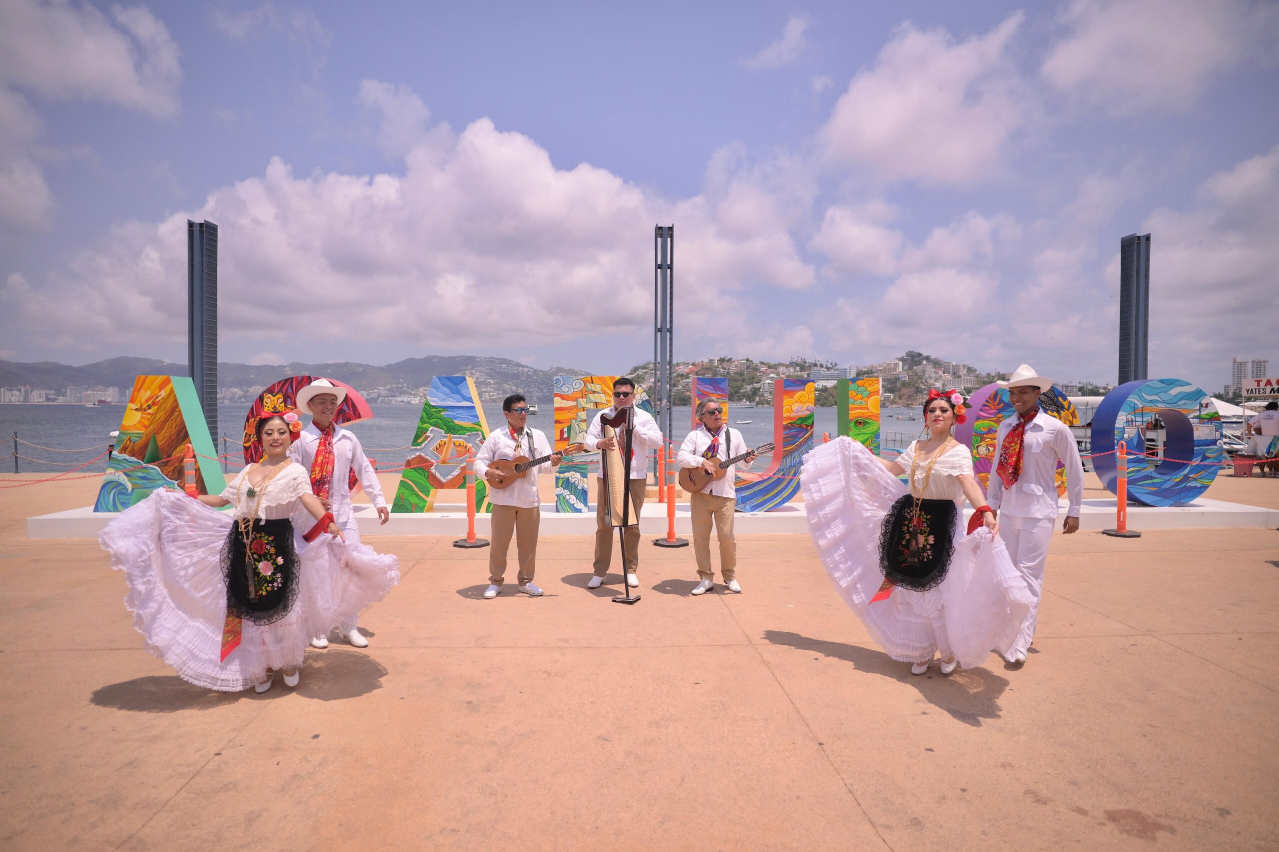 Una Fotografía A Plena Luz Del Día En Una Plaza Frente Al Mar, Donde Un Grupo Folclórico Veracruzano Posa Frente A Las Letras Monumentales De &Quot;Acapulco&Quot;.