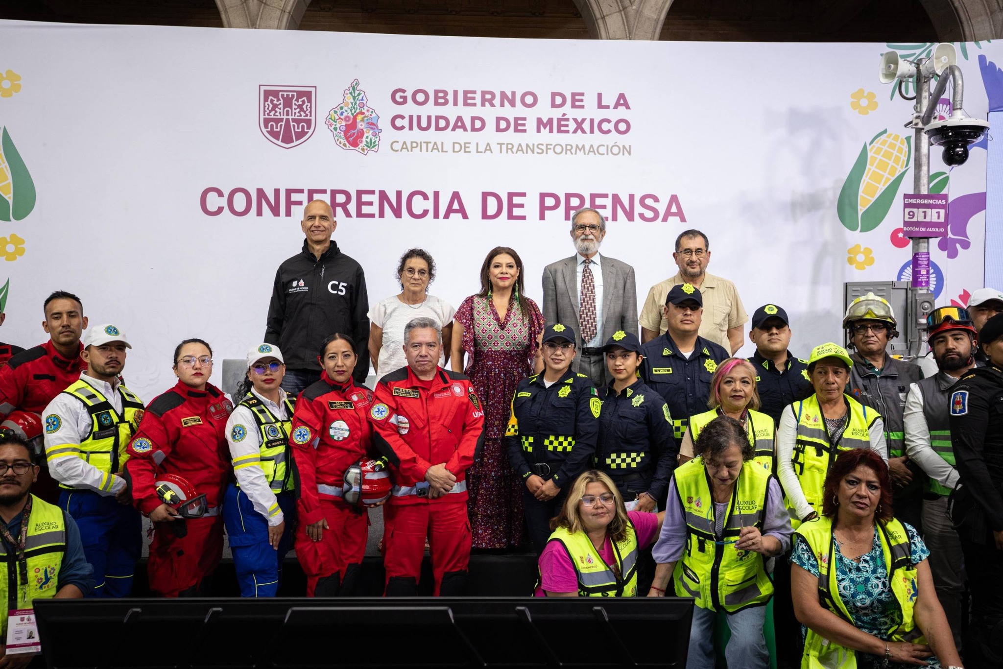 Fotografía De La Jefa De Gobierno De La Ciudad De México, Clara Brugada Molina, Encabezando Una Conferencia De Prensa Sobre El Primer Simulacro Nacional 2026. Se Encuentra Al Centro, Acompañada Por Funcionarios Y Un Grupo Diverso De Elementos De Los Cuerpos De Emergencia, Seguridad Y Protección Civil, Quienes Visten Sus Uniformes Oficiales En Colores Rojo, Azul Y Chalecos De Alta Visibilidad.