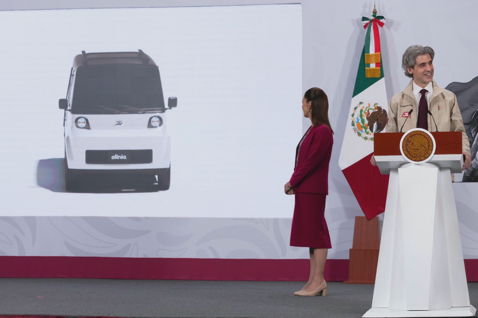 "resultados que transforman": claudia sheinbaum presenta olinia, el primer minivehículo eléctrico 100% mexicano la revista del sureste mx La Presidenta Claudia Sheinbaum Pardo En El Estrado De &Quot;Las Mañaneras Del Pueblo&Quot;. A Su Lado, Una Pantalla Proyecta El Prototipo Del Minivehículo Eléctrico Mexicano &Quot;Olinia&Quot;, Un Auto Compacto De Color Blanco Con Diseño Moderno.