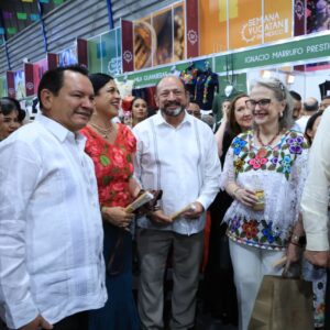 El "renacimiento maya" conquista la capital: inauguran la semana de yucatán en méxico 2026 la revista del sureste mx Una Fotografía Grupal Capturada Durante La Inauguración De La Semana De Yucatán En México 2026 En El Palacio De Los Deportes. En El Centro Destaca El Gobernador De Yucatán, Joaquín Díaz Mena, Vistiendo Una Guayabera Blanca De Gala. A Su Lado Se Encuentra La Subsecretaria De Turismo Federal, Nathalie Desplas Puel, Portando Un Huipil Tradicional Blanco Con Coloridos Bordados De Flores. Los Acompañan Otros Funcionarios Y Mujeres Vestidas Con Trajes Típicos Regionales (Ternos Y Huipiles) De Colores Vibrantes Como Rojo Y Azul.