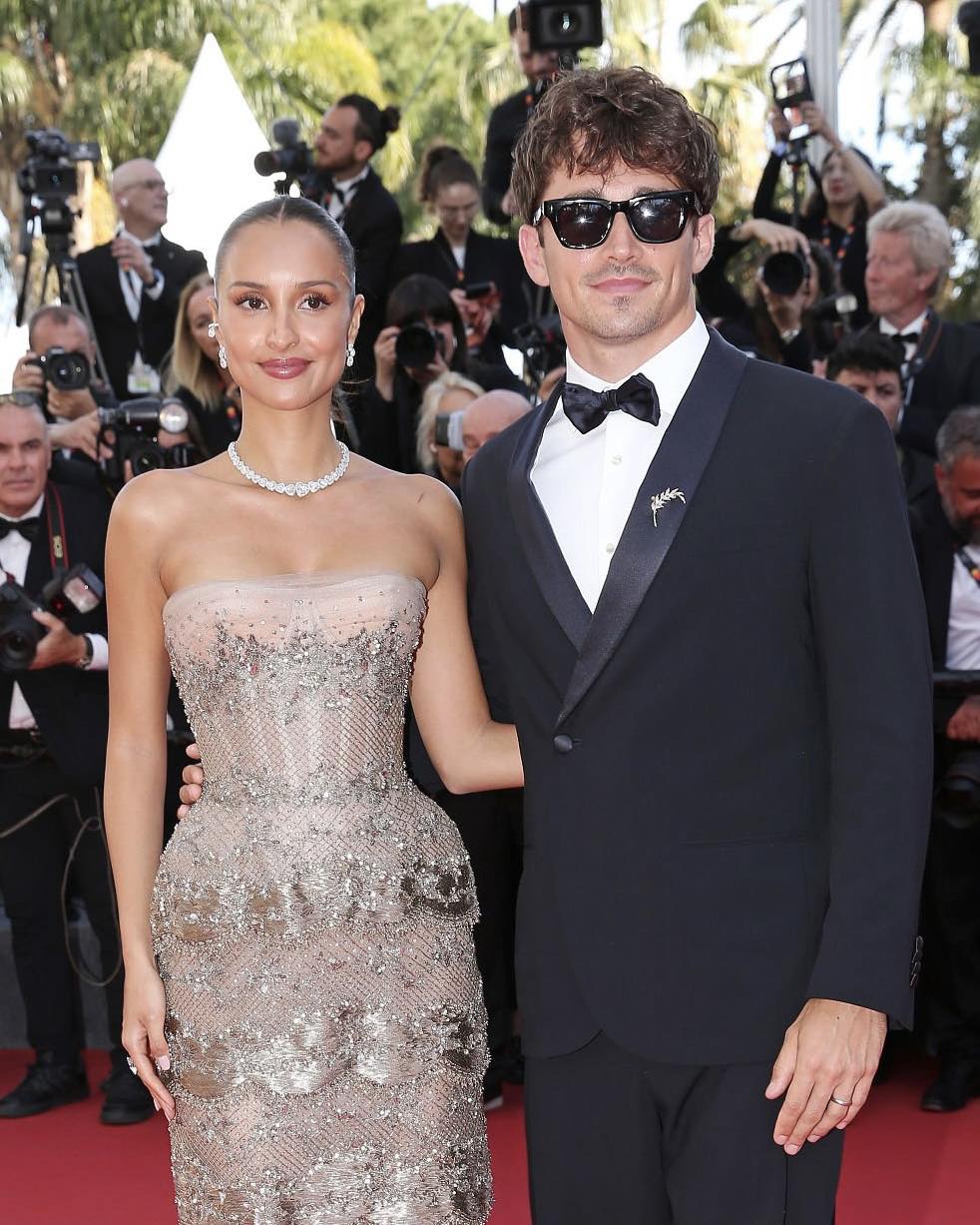 La alfombra roja de cannes 2026: entre el esplendor de la alta costura y los límites del estricto protocolo 'black tie' la revista del sureste mx Otografía De Prensa De Charles Leclerc Y Alexandra Saint Mleux Posando Juntos Sobre La Alfombra Roja En La Entrada Del Festival De Cannes. A La Izquierda, Alexandra Viste Un Elegante Vestido De Gala Strapless En Tul De Color Beige O Nude Con Pedrería Sutil Incrustada Y Un Collar Brillante De Diamantes.