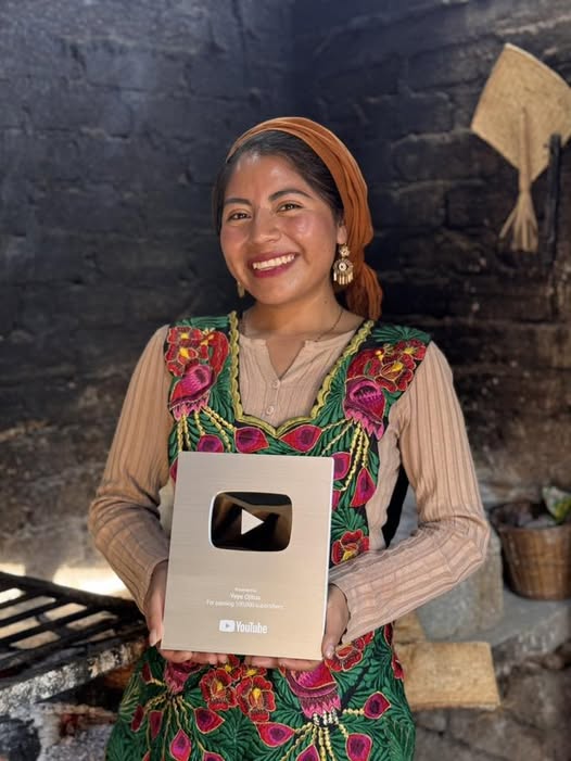 De santa maría tlahuitoltepec para el mundo: la oaxaqueña "ye ye ojitos" recibe el botón de plata de youtube la revista del sureste mx Fotografía En Primer Plano Vertical Y Enfoque Nítido De Jezcica González Gómez (&Quot;Ye Ye Ojitos&Quot;). La Creadora De Contenido Sonríe Con Calidez Directamente A La Cámara. Lleva Un Pañuelo De Color Naranja Ocre Que Cubre Su Cabello Recogido Y Luce Aretes Colgantes Artesanales En Tono Dorado.
