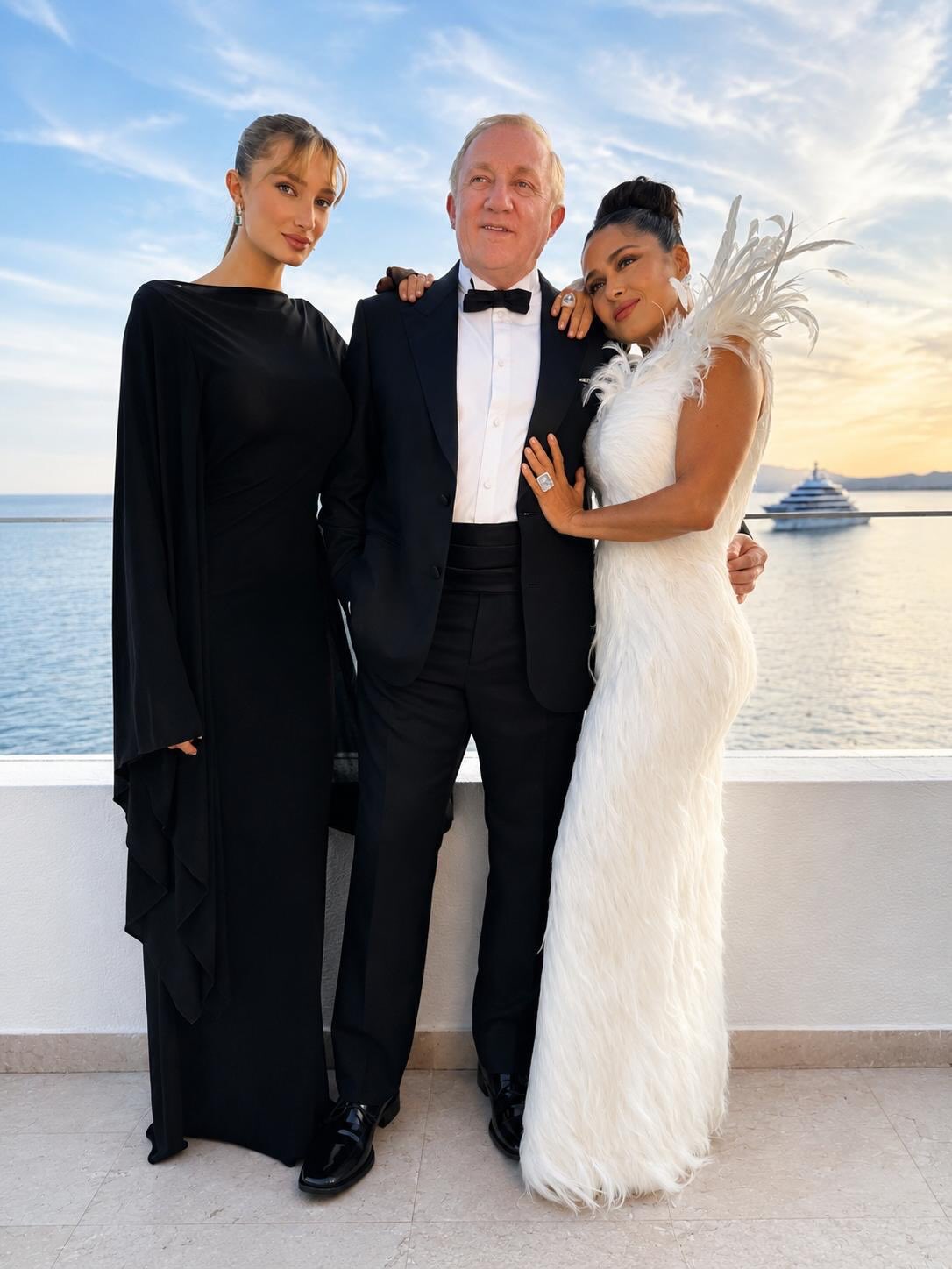 Cannes 2026: la veracruzana salma hayek da cátedra de elegancia con un look angelical la revista del sureste mx Fotografía De Prensa De Plano Entero Que Muestra A Tres Personas Posando Juntas Al Atardecer En Una Terraza Con Barandal De Cristal Y Vista Al Mar Mediterráneo. A La Izquierda, La Modelo Mathilde Pinault Viste Un Vestido Largo Negro De Manga Larga Y Cuello Alto. Al Centro, El Empresario François-Henri Pinault.