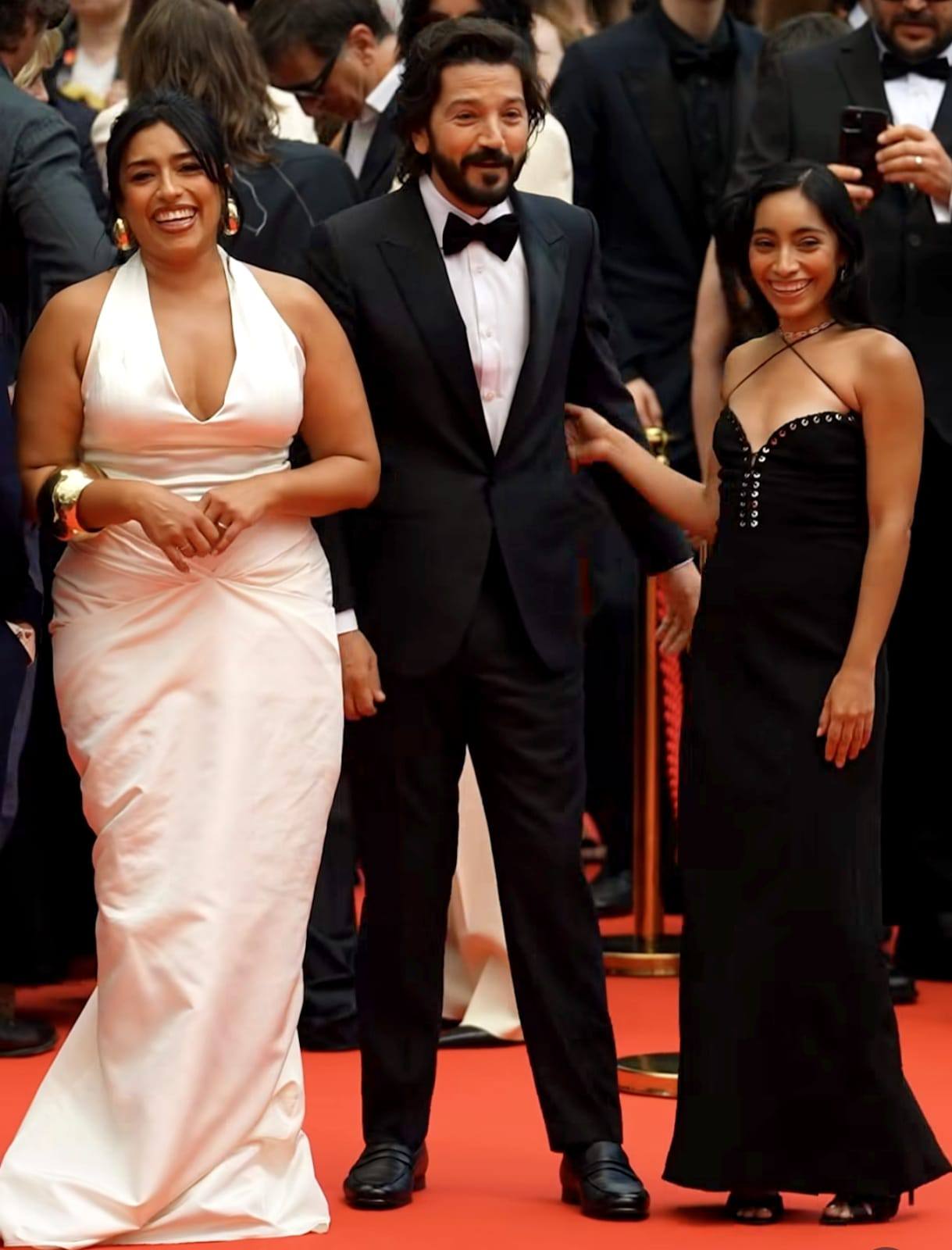 Los Actores Mexicanos Adriana Paz, Diego Luna Y Anna Díaz Posan Juntos En La Alfombra Roja Del Festival De Cannes 2026. Adriana Paz Viste Un Elegante Vestido Blanco De Escote Profundo; Diego Luna Luce Un Esmoquin Negro Clásico Con Moño; Y Anna Díaz Porta Un Vestido Negro Con Detalles De Estoperoles. Los Tres Sonríen A La Prensa Durante La 79ª Edición Del Certamen.