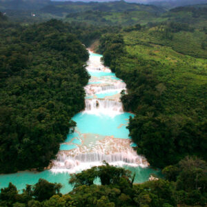 México es hogar de cascadas espectaculares: guía de las imperdibles que debes conocer la revista del sureste mx Vista Aérea Panorámica Y En Picado De Un Sistema De Cascadas Escalonadas De Un Intenso Color Azul Turquesa. El Cuerpo De Agua Fluye En Niveles Descendentes, Formando Terrazas Naturales De Roca Calcárea Blanquecina Y Pozas Anchas De Aguas Cristalinas. El Cauce Está Completamente Flanqueado E Inmerso En Una Densa Y Exuberante Selva Tropical De Color Verde Intenso, Con Árboles Altos Que Cubren Las Laderas Circundantes.