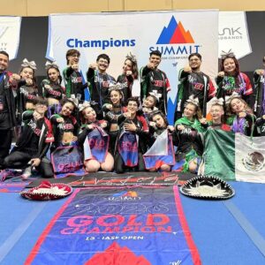 Otografía De La Delegación Arce De Mexicali En Orlando, Florida, Celebrando Su Triunfo Como Campeones Del Mundo En The Summit 2026. Los 21 Atletas Mexicanos Posan Con Orgullo Portando La Bandera De México Y Sombreros Charros Sobre El Tapete Azul.