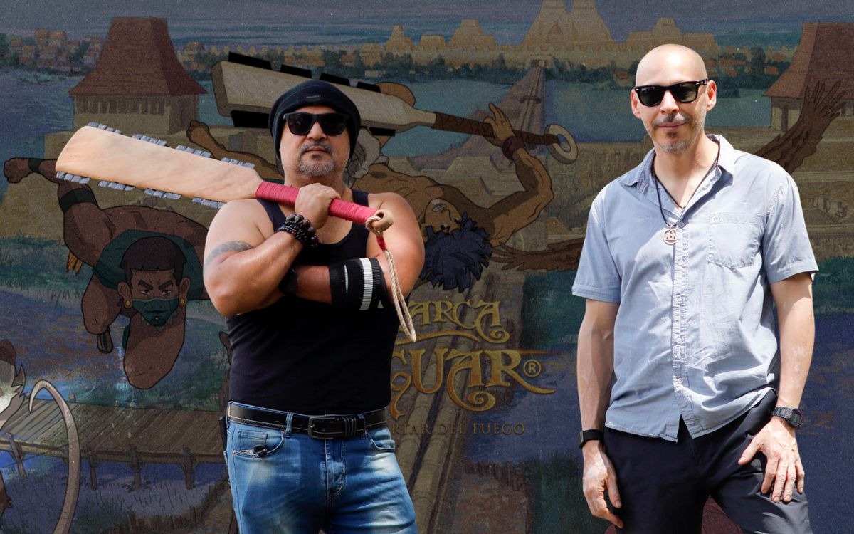 Orgullo nacional en cannes: "la marca del jaguar" de víctor mayorga conquista el marché du film con una épica mexica de animación la revista del sureste mx Fotografía De Prensa En Plano Medio Que Muestra A Dos Hombres Posando De Pie Bajo La Luz Del Sol Frente A Un Gran Muro Promocional Ilustrado.