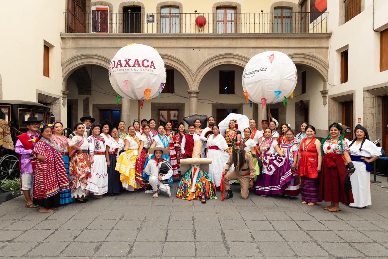 El corazón cultural de méxico late en la capital: presentan el programa oficial de “julio, mes de la guelaguetza 2026” la revista del sureste mx Una Fotografía De Gran Angular Que Captura A Un Grupo Grande De Más De 30 Personas Posando En El Patio Adoquinado De Un Edificio Colonial Español De Dos Pisos Con Arcos De Piedra. Todos Los Individuos Visten Coloridos Y Variados Trajes Tradicionales Oaxaqueños (Huipiles, Faldas Largas, Sombreros De Paja).
