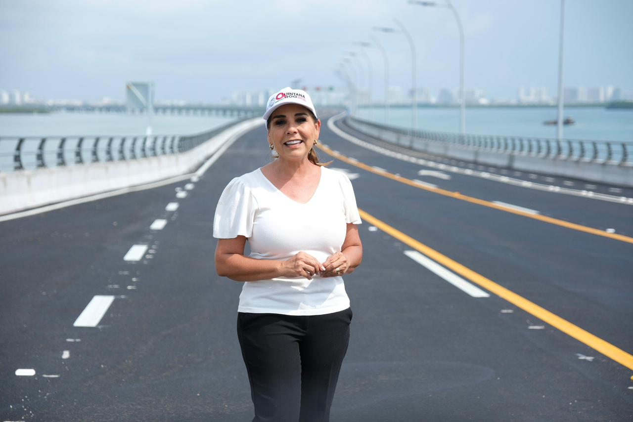 Texto Alternativo (Alt Text) La Gobernadora De Quintana Roo, Mara Lezama Espinosa, Aparece De Pie En El Centro De Uno De Los Carriles Del Nuevo Puente Vehicular Nichupté En Cancún. Viste Una Blusa Blanca, Pantalón Negro Y Una Gorra Blanca Con Logotipos Institucionales Del Estado. Detrás De Ella Se Extiende La Moderna Estructura Vial De Asfalto Impecable Con Señalización Horizontal Blanca Y Amarilla, Que Cruza Sobre El Sistema Lagunar. Al Fondo Se Aprecia El Horizonte Con La Zona Hotelera De Cancún Bajo Un Cielo Claro.