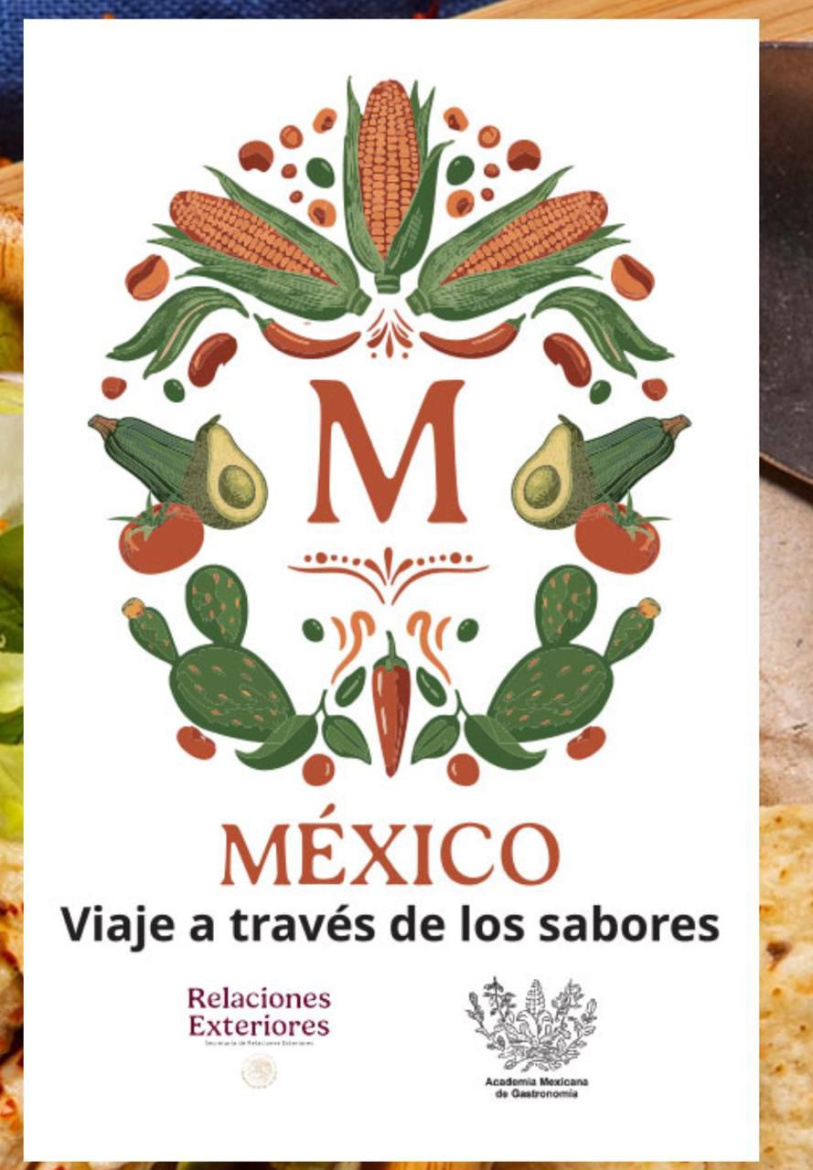 Un Primer Plano De Un Distinguido Galardón Metálico En Forma De Plato Circular, Basado En El Diseño De La Imagen Anterior. El Plato, De Metal Cepillado Con Detalles De Latón Y Esmalte Verde Oscuro Y Terracota, Presenta La Letra &Quot;M&Quot; Central Rodeada Por La Intrincada Corona Botánica De Maíz, Aguacates, Chiles, Nopales Y Tomates.