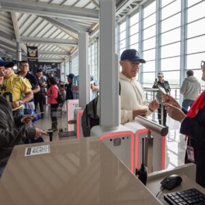 Turismo: sector alcanza récord de 5 millones 22 mil personas ocupadas en el primer trimestre de 2026 la revista del sureste mx Otografía De Reportaje En Formato Horizontal Que Muestra La Actividad Dentro De Una Moderna Terminal Aeroportuaria Iluminada Por Luz Natural Que Entra A Través De Grandes Ventanales. En El Lado Derecho, Una Agente De Aerolínea Con Uniforme Azul Marino, Pañuelo Rojo Al Cuello Y Lentes, Atiende De Manera Amable A Un Pasajero Joven Que Viste Una Sudadera Blanca Y Gorra Azul. E