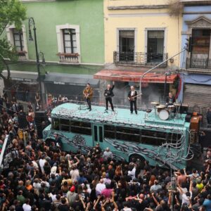 U2 en méxico: la banda irlandesa recibe invitación formal para el zócalo la revista del sureste mx Fotografía Aérea En Picado Que Captura A La Banda Irlandesa U2 Actuando Sobre El Techo De Un Autobús Escolar Color Turquesa En El Centro Histórico De La Ciudad De México. El Autobús Está Decorado Con Grafitis De Cadenas Y Una Rosa Negra, Obra Del Artista Chavis Mármol. Sobre El Vehículo Se Encuentran Bono, The Edge, Adam Clayton Y Larry Mullen Jr. Con Sus Instrumentos Y Batería. Una Multitud Masiva De Cientos De Fanáticos Rodea El Autobús En Una Calle Estrecha Flanqueada Por Edificios Históricos Con Balcones Y Fachadas De Colores Verde Y Amarillo.