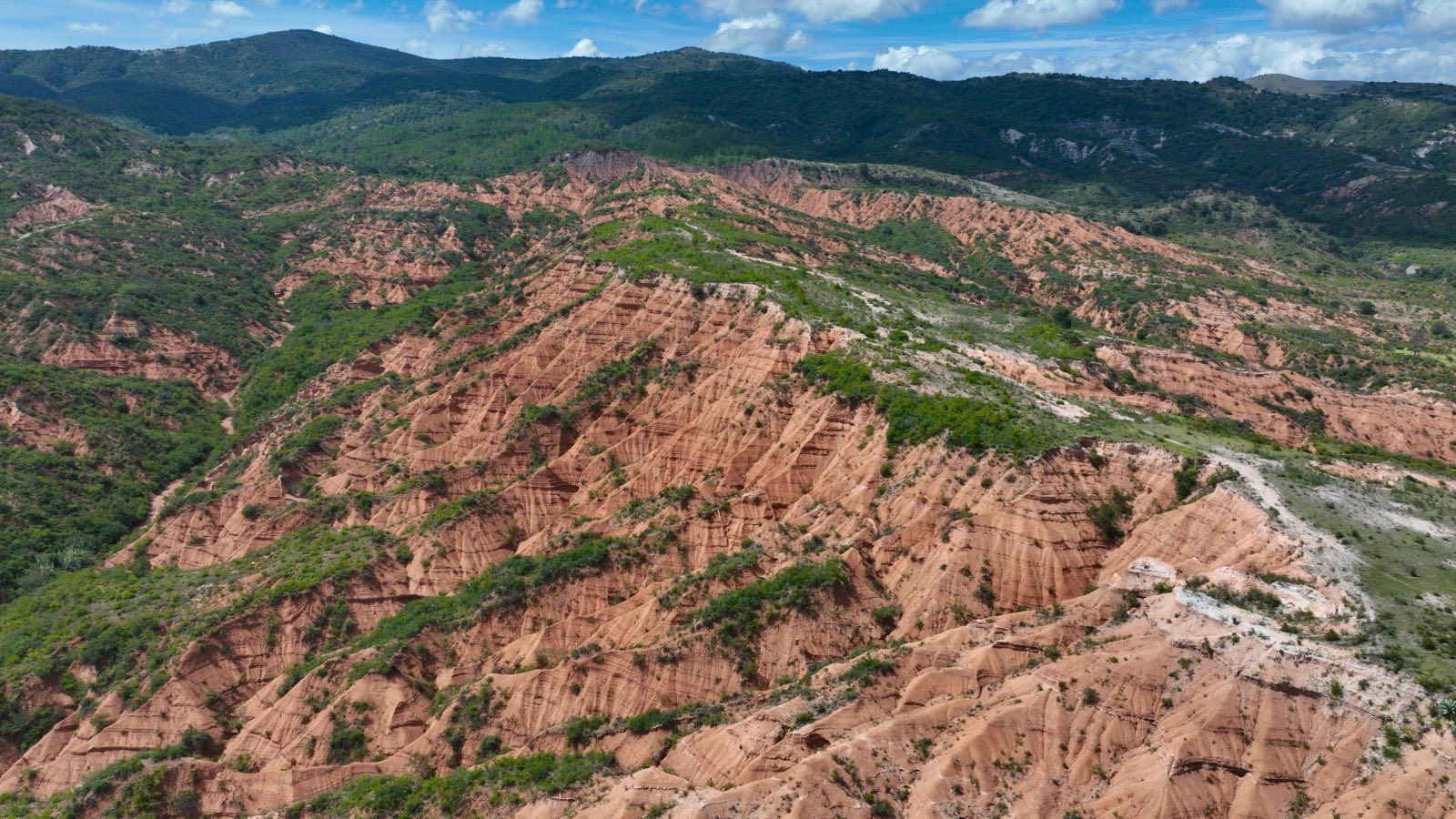 Geoparque mundial mixteca alta: un viaje por la historia geológica y el corazón de oaxaca la revista del sureste mx Vista Aérea Del Geoparque Mundial Mixteca Alta En Oaxaca, México. La Imagen Muestra Un Terreno Montañoso Con Laderas De Tierra Rojiza Marcadas Por Una Intensa Erosión Natural Que Forma Surcos Profundos Y Patrones Geométricos En El Relieve.