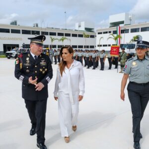 Cancún: mara lezama y la guardia nacional activan coordinación de seguridad para blindar el tren maya, aeropuertos y destinos turísticos la revista del sureste mx Una Fotografía En Plano Entero Y Ángulo Contrapicado Que Muestra A La Gobernadora De Quintana Roo, Mara Lezama, Caminando Y Conversando En Una Explanada Junto Al General De Brigada Sergio López Acosta, Coordinador Estatal De La Guardia Nacional. Mara Lezama Viste Un Conjunto Formal Completamente Blanco De Blusa Y Pantalón. El General Porta Su Uniforme De Gala Oscuro Con Insignias Militares Y Gorra.