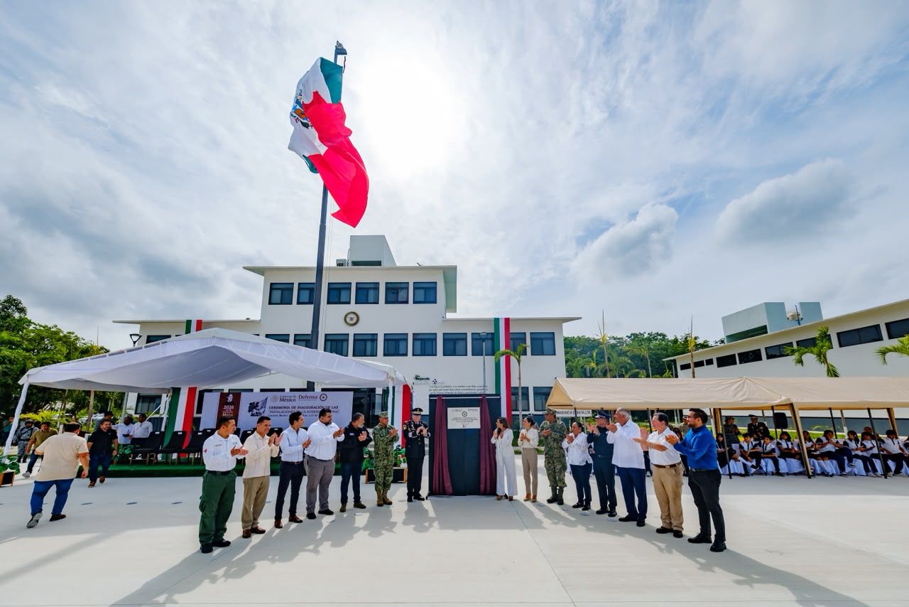 Cancún: mara lezama y la guardia nacional activan coordinación de seguridad para blindar el tren maya, aeropuertos y destinos turísticos la revista del sureste mx Una Fotografía En Plano General Que Captura El Momento Posterior A La Develación De La Placa Conmemorativa En Las Nuevas Instalaciones De La Guardia Nacional En Cancún. En El Centro Del Amplio Patio Exterior, Una Gran Bandera De México Ondea En Lo Alto De Un Asta Vertical Bajo Un Cielo Parcialmente Nublado.