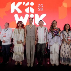 Un Presídium De Ocho Autoridades Y Funcionarias Públicas Posa De Pie En Línea Recta Sobre Un Escenario Oscuro Durante La Inauguración De La Feria Turística. Al Fondo, Destaca Una Enorme Pantalla Led De Color Rojo Brillante Con El Logotipo Oficial Del Evento En Letras Estilizadas Blancas Que Dice &Amp;Quot;K'Íiwik 2026&Amp;Quot;. De Izquierda A Derecha, Se Observa A Darío Flota Ocampo Con Guayabera Blanca