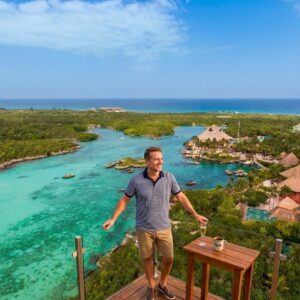 Guía de aventuras en el caribe: 4 destinos y experiencias imperdibles para sorprender a papá en cancún la revista del sureste mx Un Hombre Sonriente De Pie En Un Mirador De Madera Con Barandillas De Vidrio, Contemplando Una Impresionante Caleta Turquesa Rodeada De Selva Verde Y El Mar Caribe. El Paisaje Incluye Estructuras Con Techos De Paja, Y A Su Lado Hay Una Pequeña Mesa Con Una Taza Que Dice &Amp;Quot;Papi&Amp;Quot; Y Una Copa.