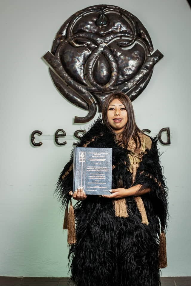 Joven indígena de chiapas rompe barreras al lograr su doctorado la revista del sureste mx Fotografía De Susi Bentzulul En El Centro, Vistiendo Indumentaria Tradicional De San Juan Chamula Con Un Chuj Negro De Lana Y Detalles Dorados, Flanqueada Por Sus Padres. Al Fondo, Se Aprecia El Logotipo Metálico Del Cesmeca.