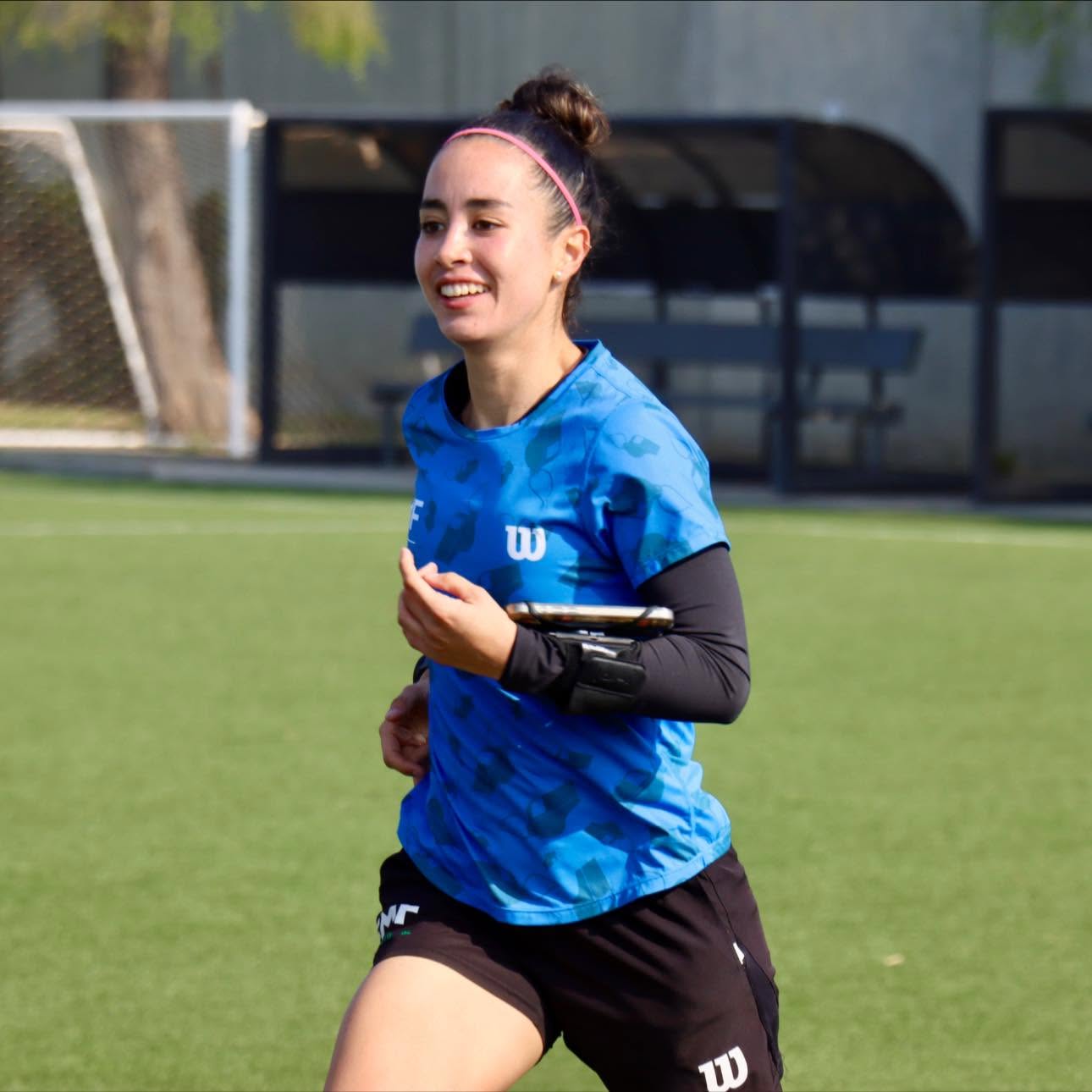 ¡orgullo nacional! Katia itzel garcía será la primera mexicana en pitar como árbitra central en un mundial varonil la revista del sureste mx La Árbitra Mexicana Katia Itzel García Sonríe Mientras Corre Durante Una Sesión De Entrenamiento En Una Cancha De Fútbol De Césped Verde. Viste Una Playera Deportiva Azul Con Mangas Largas Negras Debajo, Shorts Negros Y Una Banda Rosa En El Cabello, Llevando Un Dispositivo En El Brazo Izquierdo. Al Fondo Se Observa Una Portería Y Bancas De Entrenamiento Difuminadas.