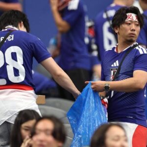 Lección de civismo en el mundial 2026: aficionados de japón limpian el estadio tras empate ante países bajos la revista del sureste mx Otografía En Plano Medio De Un Grupo De Aficionados De La Selección De Fútbol De Japón Sonriendo Alegremente En Las Gradas De Un Estadio Deportivo Cubierto De Gran Capacidad. Los Hinchas, En Su Mayoría Jóvenes, Portan Camisetas Oficiales De Color Azul Y Bandas Festivas En La Cabeza. Sostienen En Alto Bolsas De Plástico De Color Azul Infladas Mientras Celebran Durante El Evento. Al Fondo Se Aprecia La Arquitectura Techada Del Recinto Y La Iluminación Masiva De Las Instalaciones.