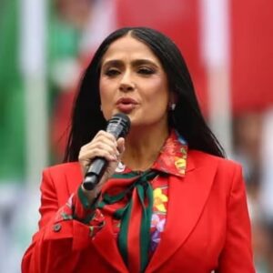 Icono de estilo y diplomacia: salma hayek conquista la inauguración del mundial 2026 con un traje "rojo" la revista del sureste mx Una Fotografía De Plano Medio Que Captura A La Actriz Salma Hayek Dirigiendo Unas Palabras Al Público Durante La Inauguración De La Copa Del Mundo De La Fifa México 2026 En El Estadio Ciudad De México. Viste Un Traje Sastre En Color Rojo Intenso, Complementado Con Una Blusa Estampada De Flores Multicolores Y Una Corbata De Lazo Con Franjas Verde Y Rojo, De La Firma Gucci.