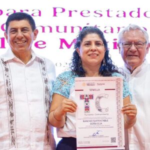 Sectur impulsa el turismo comunitario: entrega 206 distintivos y credenciales a guías especializados con oaxaca como referente nacional la revista del sureste mx Cinco Personas Posan De Pie En Un Escenario Durante Un Evento Oficial. En El Centro, Una Mujer Sonriente Sostiene Un Reconocimiento Impreso De La Secretaría De Turismo Del Gobierno De México Con El Logotipo &Amp;Quot;Tc Turismo Comunitario&Amp;Quot; Y El Nombre &Amp;Quot;Rancho Sustentable Doña Elia&Amp;Quot;. A Su Izquierda Se Encuentran La Secretaria De Turismo, Josefina Rodríguez Zamora, Vistiendo Un Conjunto Estampado En Blanco Y Negro, Y El Gobernador De Oaxaca, Salomón Jara Cruz, Con Una Guayabera Blanca Tradicional. A La Derecha De La Galardonada, Completan El Grupo Dos Funcionarios Públicos Masculinos Con Vestimenta Formal Y Artesanal. Al Fondo Se Observa Una Pantalla Con Letras En Color Rosa.