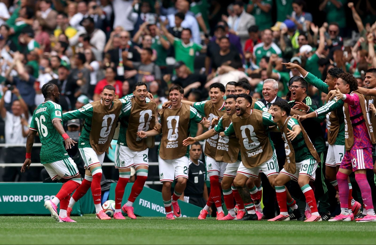 ¿y si sí? : el origen y significado de la frase que enciende la ilusión de méxico en el mundial 2026 la revista del sureste mx Fotografía En Plano Entero Que Muestra La Celebración Eufórica De Los Jugadores De La Selección Mexicana De Fútbol En El Mundial 2026 Sobre El Césped Verde De Un Estadio. Varios Futbolistas Llevan El Uniforme De Juego Con Calcetas Rojas Y Shorts Blancos, Mientras Que Otros Portan Chalecos De Entrenamiento Color Café Con El Logotipo Oficial De La Copa Del Mundo 2026. Todos Sonríen, Gritan De Júbión Y Se Abrazan Efusivamente Mirando Hacia La Derecha. Al Fondo, Las Tribunas Del Estadio Están Completamente Llenas Con Una Multitud De Aficionados Que Celebran Con Los Brazos En Alto Vistiendo Camisetas Verdes. Al Borde De La Cancha Se Observa Publicidad Verde Con Letras Blancas De La Copa Del Mundo.