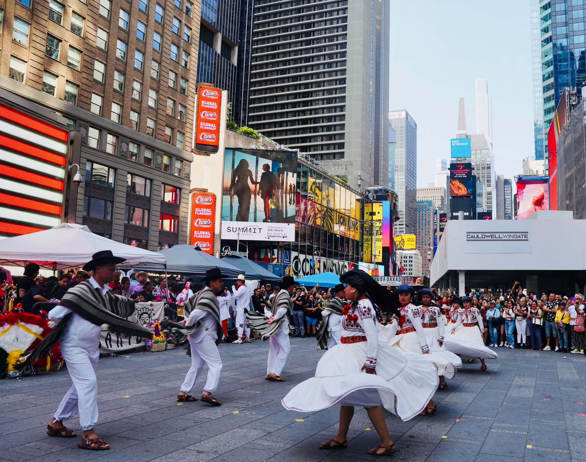 Grupo De Bailarines Oaxaqueños Con Trajes Típicos Blancos Y Ponchos Realiza Una Coreografía En La Plaza Peatonal De Times Square.