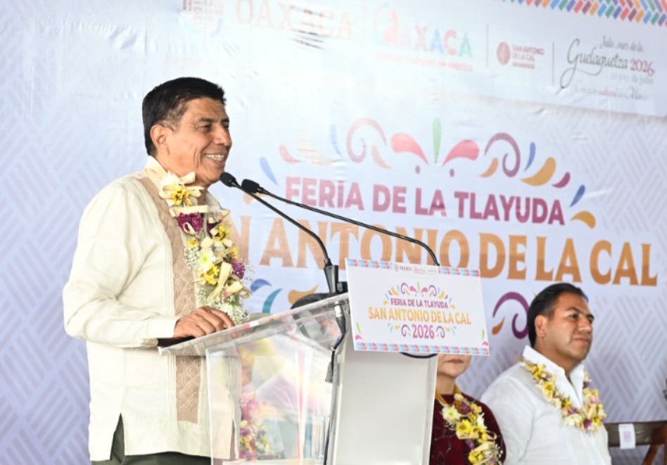 Fotografía De Salomón Jara Cruz, Gobernador De Oaxaca, Ofreciendo El Discurso Inaugural En La 13ª Feria De La Tlayuda En San Antonio De La Cal. Viste Guayabera Y Un Collar Floral. De Fondo, Una Lona Del Evento Guelaguetza 2026.