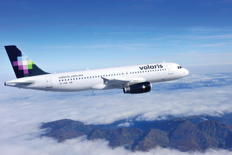 México fortalece la diversificación de mercados turísticos con crecimiento en la conectividad aérea de canadá, europa y américa latina la revista del sureste mx Una Vista Aérea De Un Avión De La Aerolínea Mexicana Volaris Volando Sobre Un Mar De Nubes Y Montañas, Ilustrando El Crecimiento De La Conectividad Internacional.
