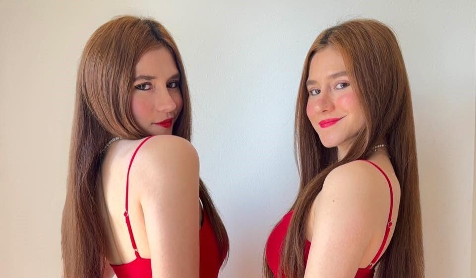 Las Gemelas Ara Y Fer Posan Sonrientes Mirando A La Cámara Con Vestidos Rojos De Tirantes.