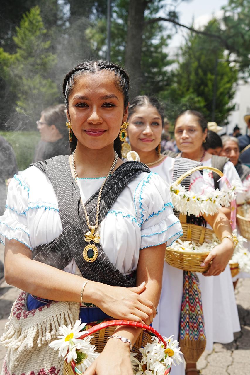 Una Joven Indígena Vestida Con Blusa Blanca Tradicional, Rebozo Cruzado Y Un Dije Dorado Encabeza Una Fila De Mujeres Con Canastas De Flores Durante La Ceremonia Ritual De Veracruz En Los Pinos.