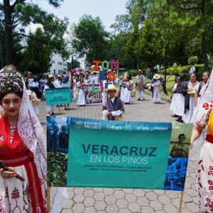 Dos Mujeres Vestidas Con Indumentaria Tradicional Veracruzana Y Tocados Elaborados Sostienen Una Lona Promocional De Veracruz En Los Pinos Durante Un Desfile Al Aire Libre.