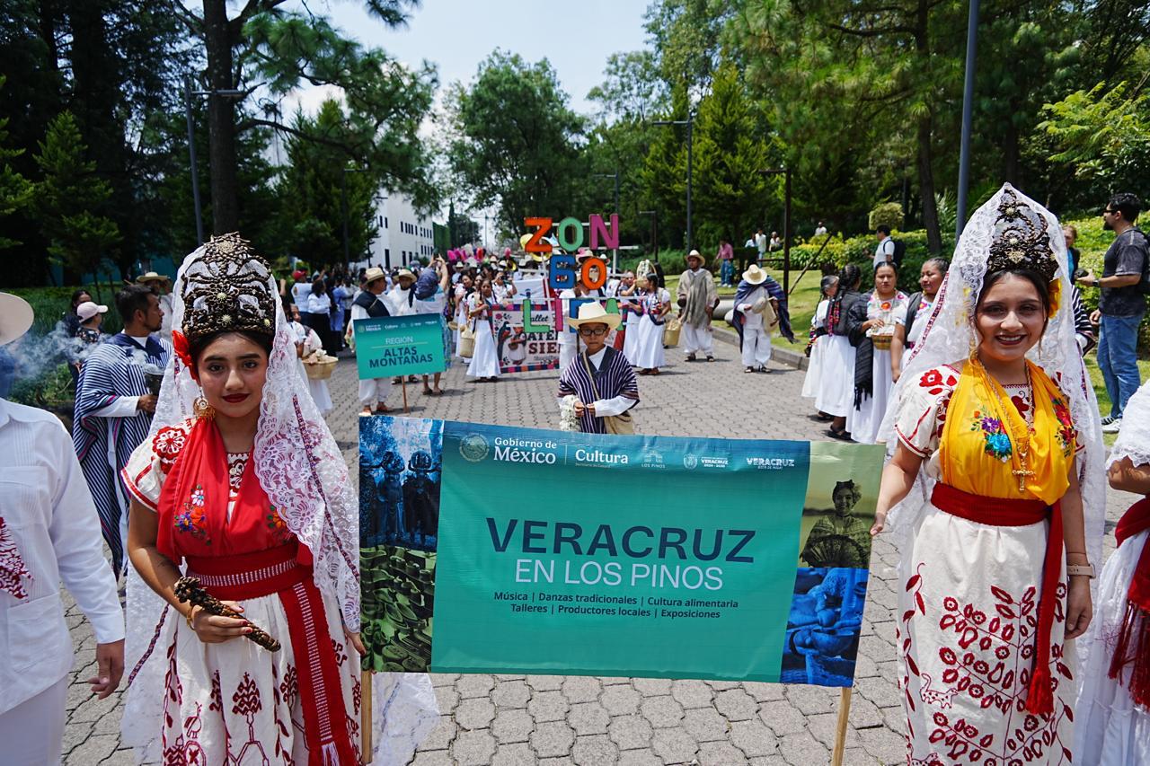 Dos Mujeres Vestidas Con Indumentaria Tradicional Veracruzana Y Tocados Elaborados Sostienen Una Lona Promocional De Veracruz En Los Pinos Durante Un Desfile Al Aire Libre.