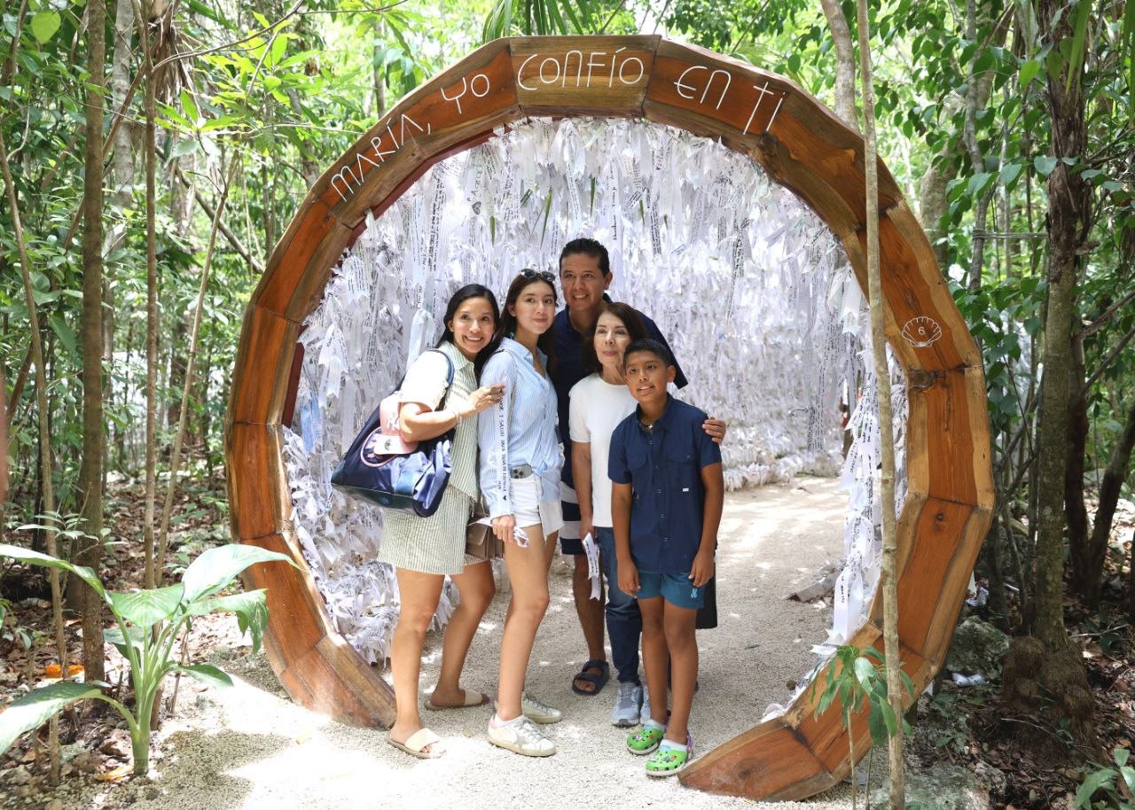 Una Familia Sonriente Posa En El Santuario De María Desatadora De Nudos, Ejemplo Del Crecimiento Del Turismo Religioso En Cancún. El Arco De Madera Tiene La Leyenda «María, Yo Confío En Ti» Y Está Decorado Con Listones De Peticiones De Peregrinos.