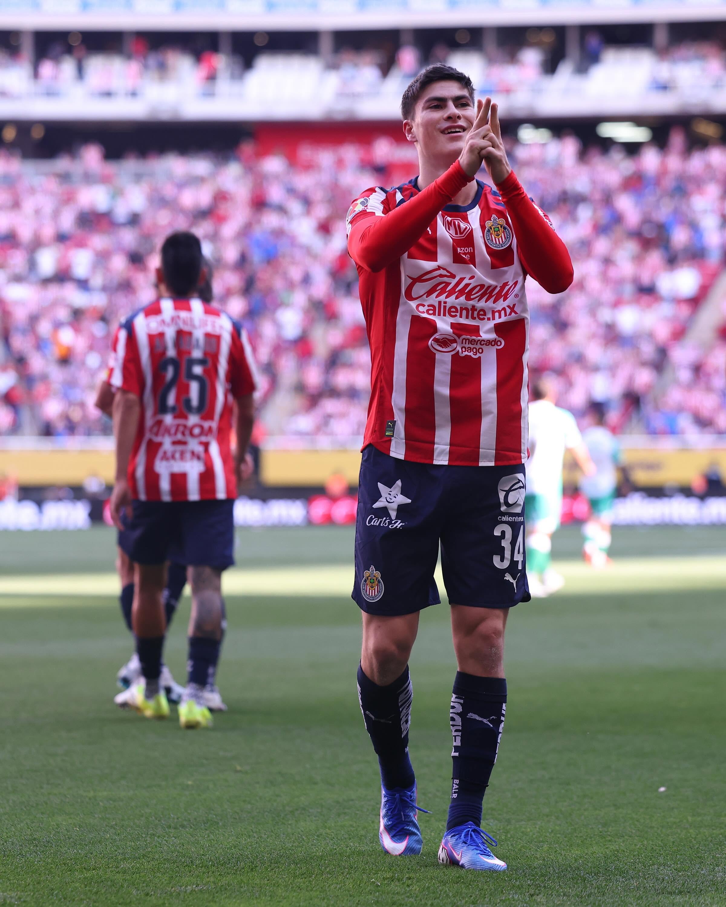 Dentro y fuera de la cancha: armando “la hormiga” gonzález asume el reto universitario desde mérida, yucatán la revista del sureste mx Un Plano Medio Del Jugador Número 34 Del Club Guadalajara, Armando &Quot;La Hormiga&Quot; González, Celebrando Un Gol En El Campo Con Los Dedos Índices Levantados, Durante Un Partido De Chivas En Un Estadio Abarrotado.