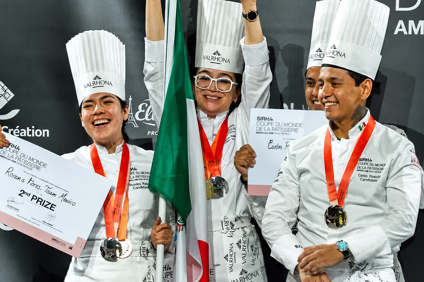 Integrantes Del Equipo Mexicano De Repostería Con Medallas, Diplomas De Segundo Lugar Y La Bandera Nacional Tras Clasificar En La Copa Del Mundo De Pastelería.
