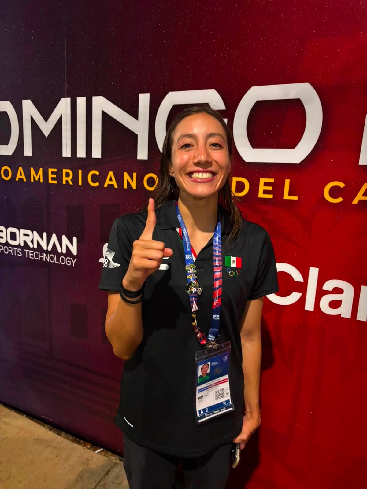 Hazaña histórica en el deporte yucateco: atletas conquistan 21 medallas en los juegos centroamericanos y del caribe la revista del sureste mx Regina Alférez Licea Sonríe Y Levanta El Dedo Índice Mostrando El Número Uno, Tras Ganar La Medalla De Oro En Equipo Mixto Técnico De Natación Artística En Santo Domingo 2026. Viste Polo Negro De La Selección Mexicana Con La Bandera De México Y Logos Del Evento. El Fondo Es Un Panel Rojo Y Púrpura De Los Juegos Centroamericanos Con Logotipos De Patrocinadores Como 'Bornan'.