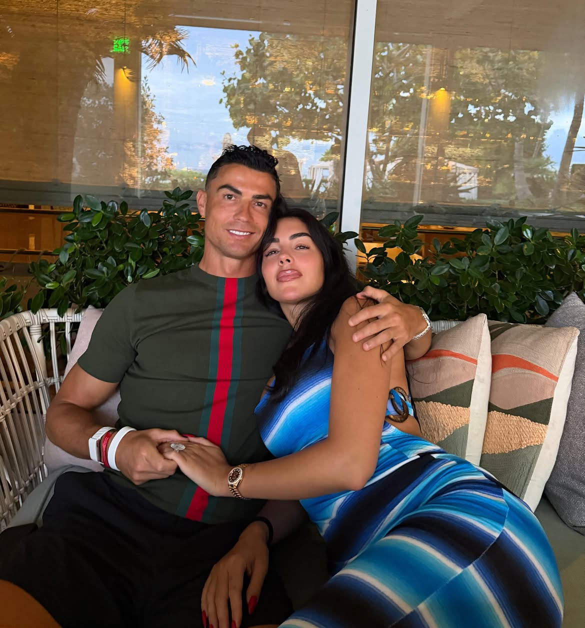 Hermetismo, fechas filtradas y lujo absoluto: todo lo que se sabe sobre la esperada boda de cristiano ronaldo y georgina rodríguez la revista del sureste mx Cristiano Ronaldo Y Georgina Rodríguez Sonrientes Y Tomados De La Mano Mientras Descansan Juntos En Un Sofá Exterior Durante Sus Vacaciones.