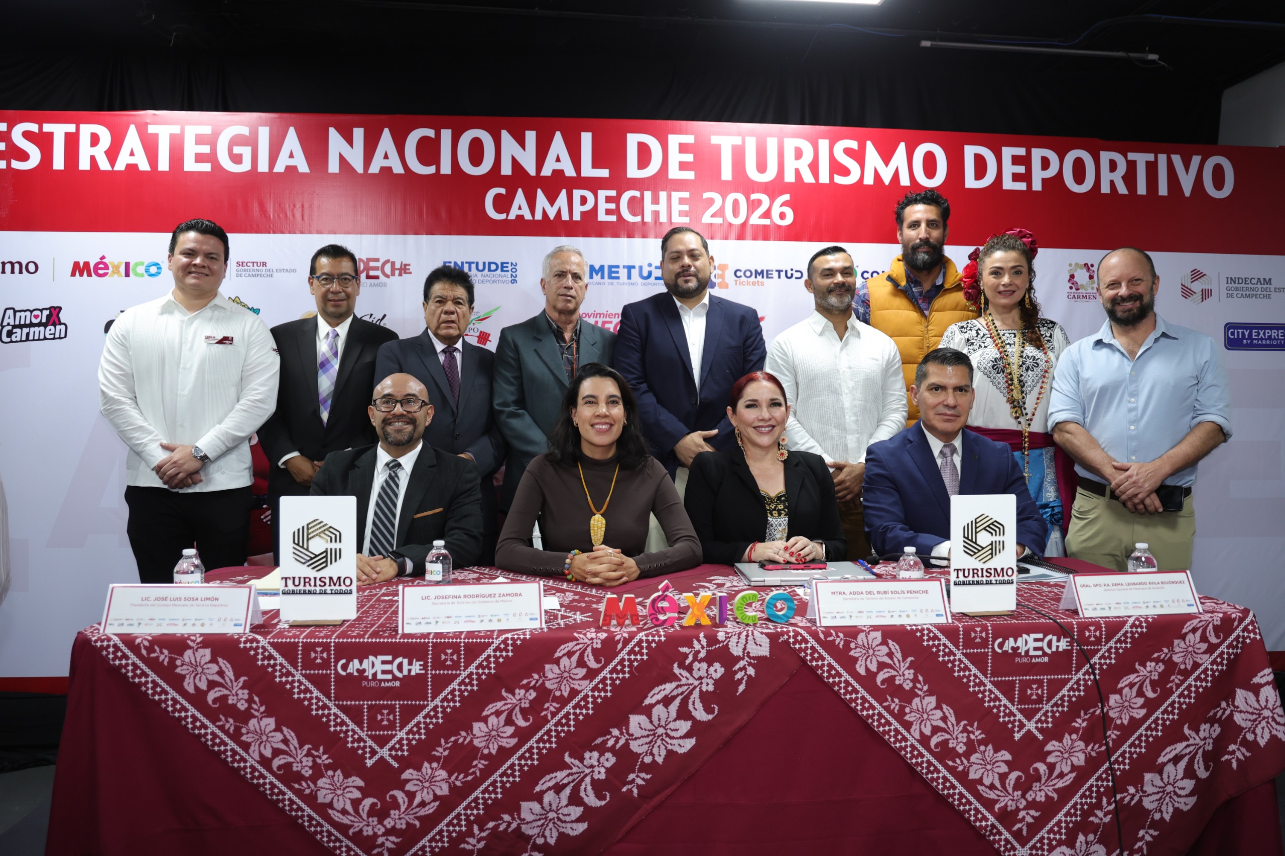 Conferencia De Prensa De La Estrategia Nacional De Turismo Deportivo Campeche 2026, Con Autoridades Federales Y Estatales Sentadas En La Mesa Principal Y Panelistas De Pie Al Fondo.