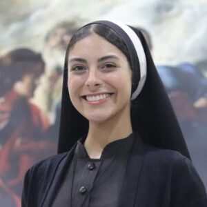 Kamila Rodrigues, Conocida Como La Hermana Eva, Sonríe A La Cámara Vistiendo Hábito Religioso Y Un Crucifijo En El Pecho.
